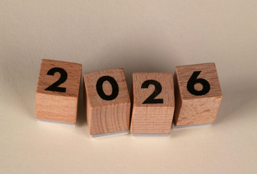wood blocks with the numbers "2026" sit on a brown background